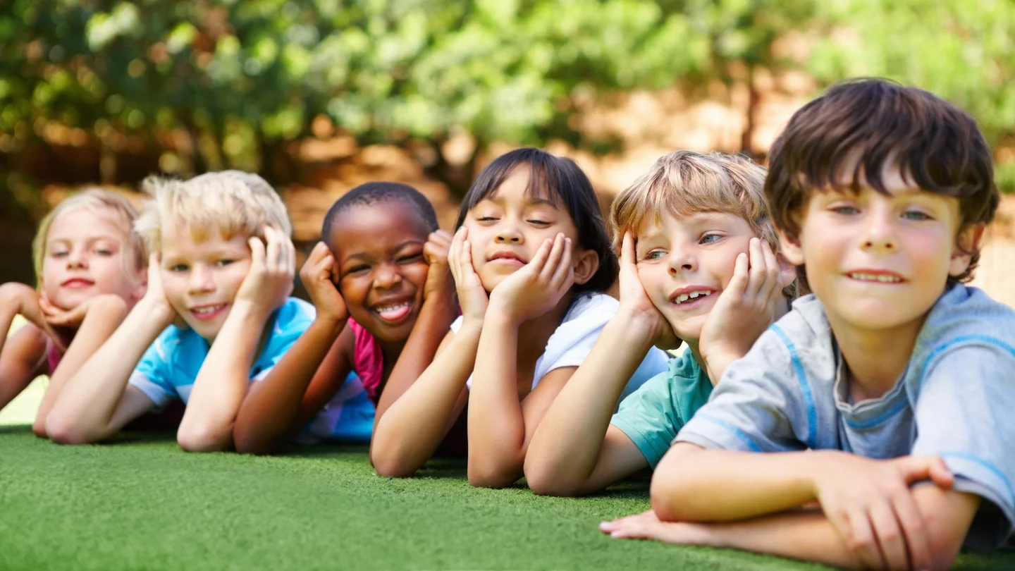 Kids lying together on the grass and smiling