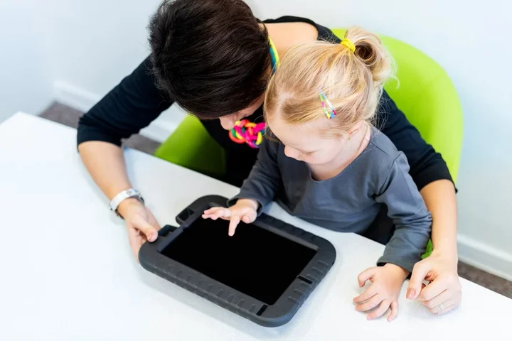 An adult and a child working together on a tablet