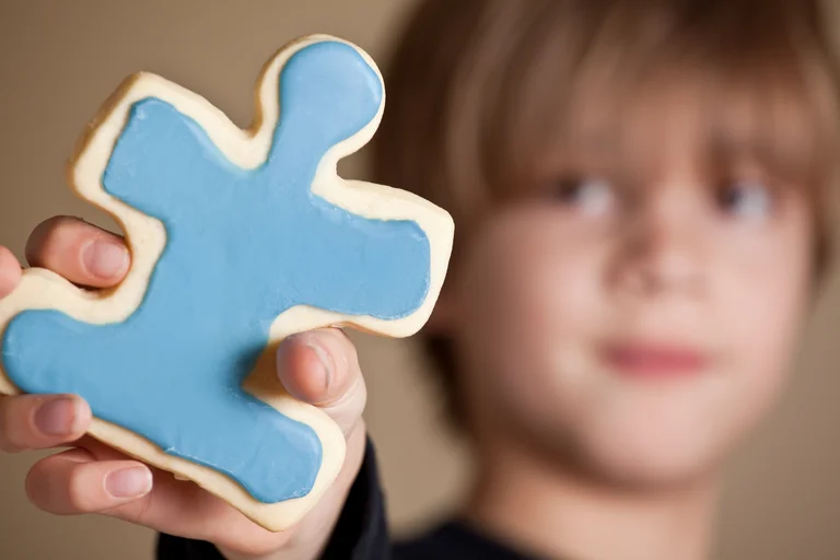 Child holds up puzzle piece cookie